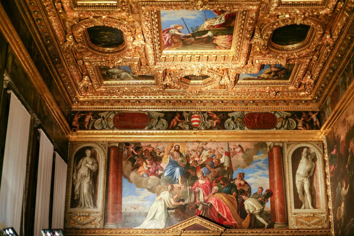Sala ornata con un soffitto dorato e intricato e un grande murale che raffigura una scena biblica con diverse figure.
