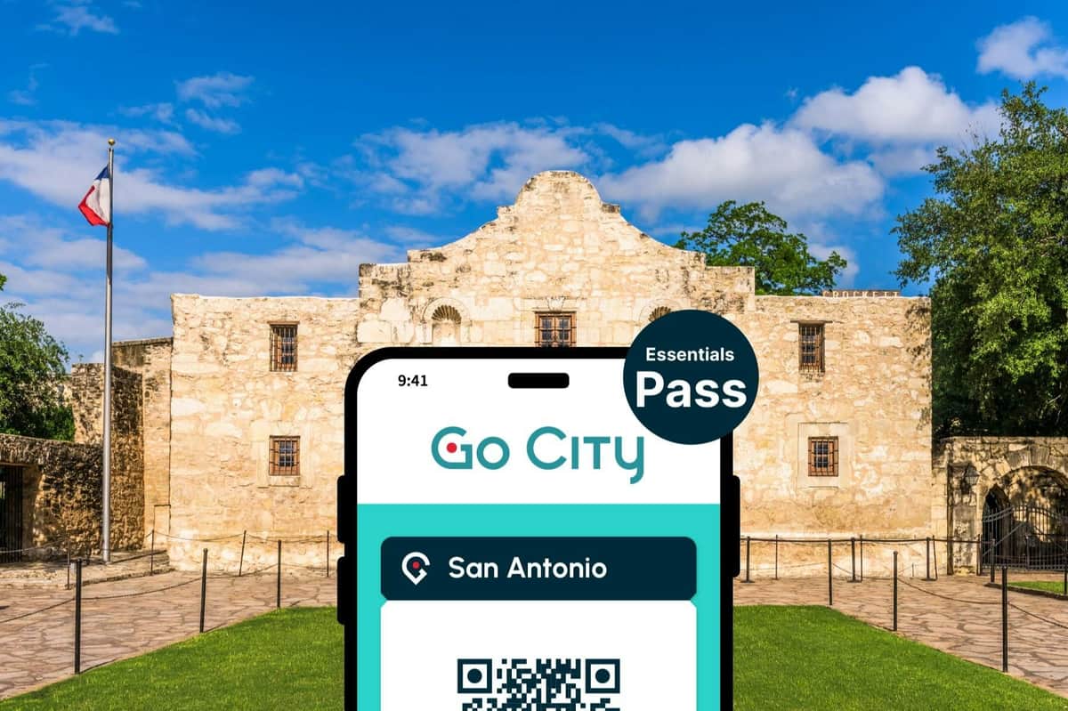 San Antonio Essentials Pass (San Antonio) Telefon komórkowy wyświetlający kod QR „Go City San Antonio Essentials Pass” nakładający się na zdjęcie Alamo pod błękitnym niebem.