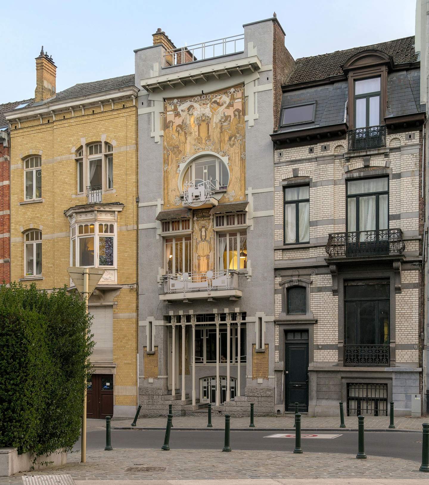 Three adjoining buildings with varying architectural styles; one features an elaborate mural and intricate balcony design.