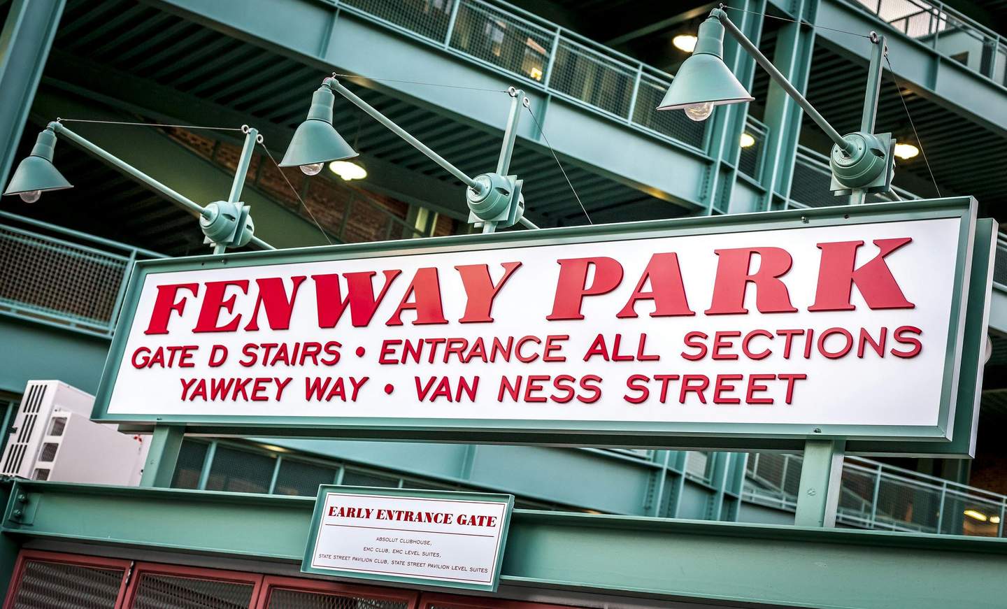 Fenway Park City Card (Boston) A sign reading "Fenway Park" with directions to Gate D, Yawkey Way, and Van Ness Street, under green lights and metal structures.