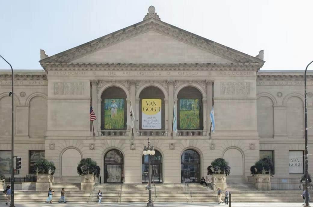 Facaden på Art Institute of Chicago med bannere til en Van Gogh-udstilling, flag og folk, der går forbi.