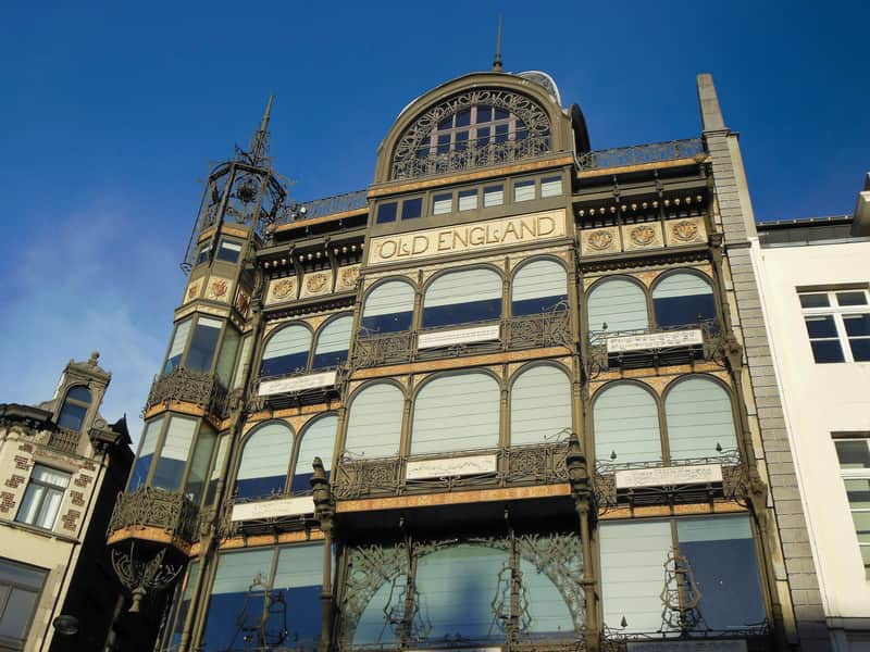 Historic building facade with ornate ironwork and arched windows, labeled "Old England," against a bright blue sky.