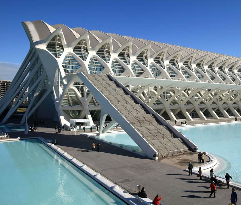 Ciudad de las artes y las ciencias City Cards & Passes (València) Modern white building with an intricate design, adjacent to reflective pools of water; people walking and gathering nearby.