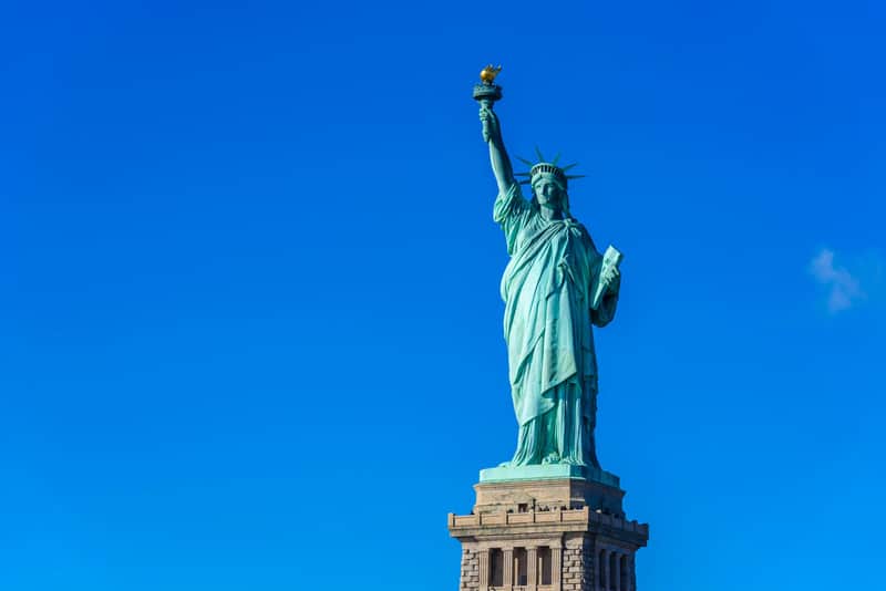 Statue of Liberty City Cards & Passes (New York) The Statue of Liberty, holding a torch and a tablet, stands against a clear blue sky.