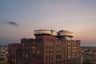 A red brick industrial-style building with modern glass circular extensions on the rooftop, set against a dusk sky.