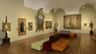 An art gallery room with paintings on the walls and multi-colored tufted benches in the center.