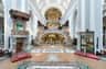An ornate church interior with a grand altar, a gilded organ, curved staircases, and intricate architectural details.