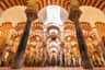 A series of ornate red and white arches supported by stone columns in a historic, cavernous interior space.