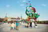Families walk near the colorful entrance of LEGOLAND Dubai, featuring a large LEGO dragon and vibrant archway under a clear sky.