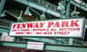 A sign reading "Fenway Park" with directions to Gate D, Yawkey Way, and Van Ness Street, under green lights and metal structures.