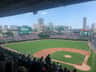 Wrigley Field during a baseball game, crowded stands, players on the field, and the scoreboard displaying "Welcome to Wrigley Field."