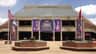 The Grand Ole Opry House with banners and flags on display, a few people near the entrance, and planters with flowers in the foreground.